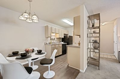 Open-concept dining area with a modern white table and chairs next to a kitchen with black appliances at Champion Hills apartments in Memphis.