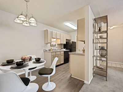 Open-concept dining area with a modern white table and chairs next to a kitchen with black appliances at Champion Hills apartments in Memphis.