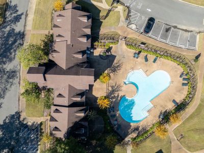 Aerial top-down view of the clubhouse building and uniquely shaped blue swimming pool at Champion Hills apartments in Memphis.
