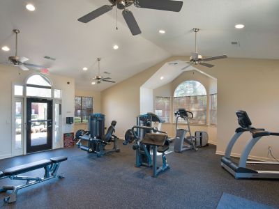 Community fitness center featuring modern workout machines, a treadmill, elliptical, and weight bench at Champion Hills apartments in Memphis