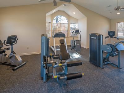 On-site resident gym equipped with a stationary bike, treadmill, and weight training machines at Champion Hills apartments in Memphis.