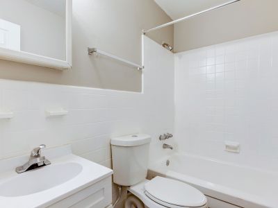 Classic apartment bathroom featuring a white vanity sink, toilet, and a white tiled tub and shower combination at Cherry Creek in Memphis.