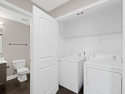 In-unit laundry closet featuring a white washer and dryer next to a bathroom with polished concrete floors at the Lofts in Town Square in Southaven.