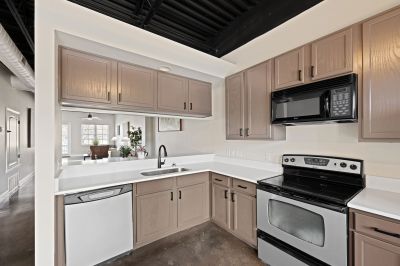 Upgraded kitchen corner showcasing brown cabinetry, white countertops, and a stainless steel stove at the Lofts in Town Square loft apartments in Southaven.