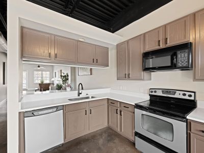 Upgraded kitchen corner showcasing brown cabinetry, white countertops, and a stainless steel stove at the Lofts in Town Square loft apartments in Southaven.
