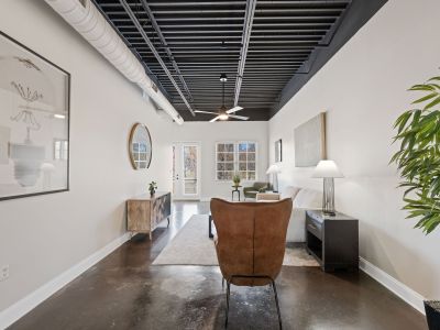 Spacious open-concept living area with a black industrial ceiling, white exposed ductwork, and polished concrete flooring at the Lofts in Town Square in Southaven.