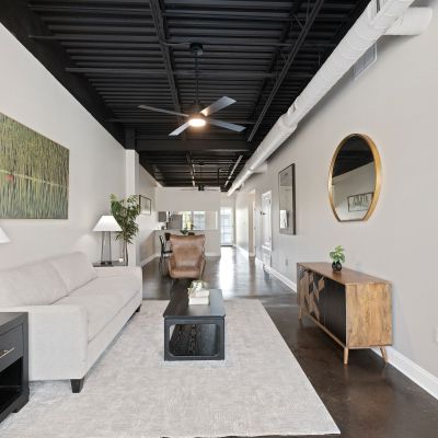 Long interior living area showing a wooden console table, round gold wall mirror, and industrial details at the Lofts in Town Square in Southaven.