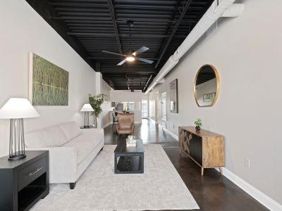 Long interior living area showing a wooden console table, round gold wall mirror, and industrial details at the Lofts in Town Square in Southaven.