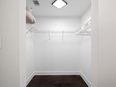 Empty walk-in closet with white wire organizational shelving and a dark stained concrete floor at the Lofts in Town Square loft apartments in Southaven.