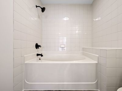 Modern apartment bathroom featuring a deep soaking tub surrounded by clean white wall tiles and sleek matte black fixtures at the Lofts in Town Square loft apartments in Southaven.