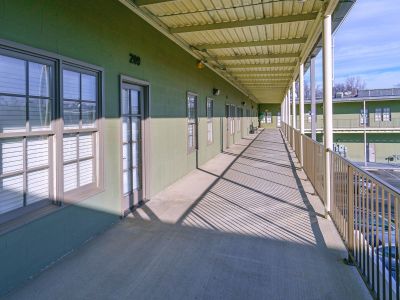 Covered outdoor resident walkway with olive green walls and metal railings outside the homes at the Lofts in Town Square loft apartments in Southaven.