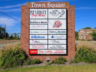 Large brick monument sign for Town Square highlighting local businesses and information for leasing at the Lofts loft apartments in Southaven.