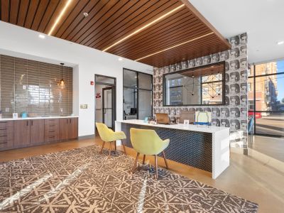 Modern leasing office lobby desk under a slatted wood ceiling feature with geometric wallpaper at Madison@McLean Midtown apartments in Memphis.
