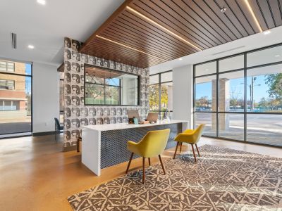 Bright leasing office reception area showcasing large storefront windows and a mosaic-tiled desk at Madison@McLean Midtown apartments in Memphis.
