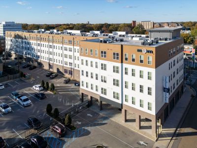 Aerial exterior view of the multi-story Madison@McLean residential community building and gated parking lot in Midtown apartments, Memphis.