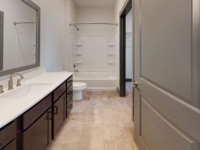 Spacious apartment bathroom featuring a long dark wood vanity countertop, white sink, and a large mirror at Madison@McLean Midtown apartments in Memphis.