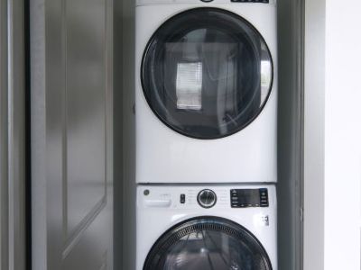 Convenient in-unit laundry closet featuring a stacked white front-load washer and dryer set at Madison@McLean Midtown apartments in Memphis.