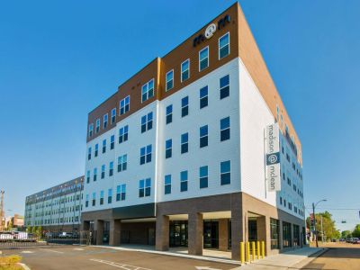 Modern exterior corner view of the Madison@McLean mid-rise residential community building under a clear blue sky in Midtown apartments, Memphis.