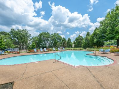 Sparkling outdoor swimming pool area showcasing concrete sun decking and pool chairs at The Magnolias apartments in Hernando, MS.