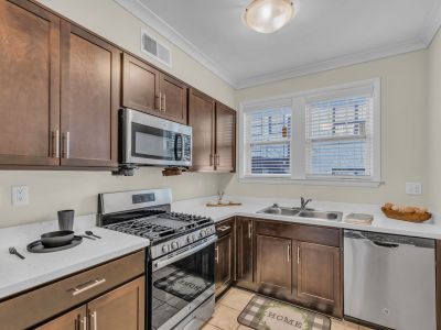Renovated apartment kitchen showing modern dark wood cabinets, stainless steel appliances, white quartz countertops, and a gas range at Stratford Place in Memphis.