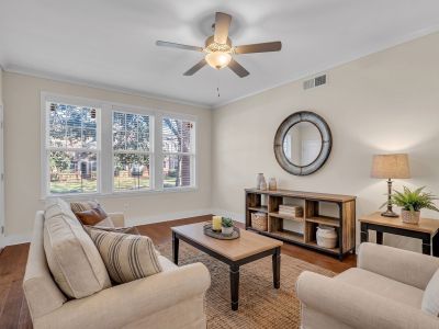 Styled interior living space showing a sofa and armchair arrangement on a woven area rug with polished hardwood floors at Stratford Place apartments in Memphis.