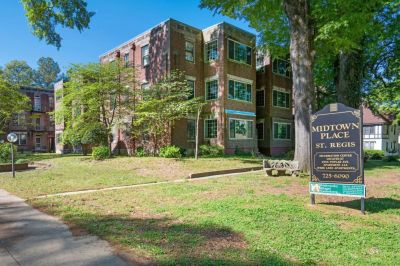Exterior view of the historic three-story brick St. Regis residential building with a community lawn sign at Midtown Place apartments in Memphis.