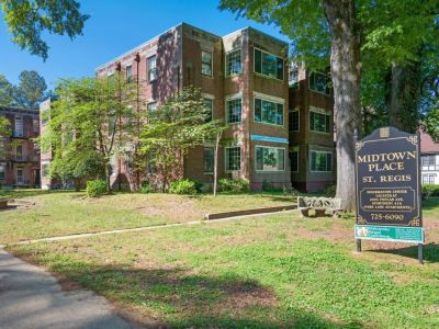 Exterior view of the historic three-story brick St. Regis residential building with a community lawn sign at Midtown Place apartments in Memphis.