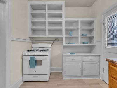 Kitchen interior view highlighting a white gas range stove and extensive built-in white shelving and cabinetry at Midtown Place The Tuscany apartments in Memphis.