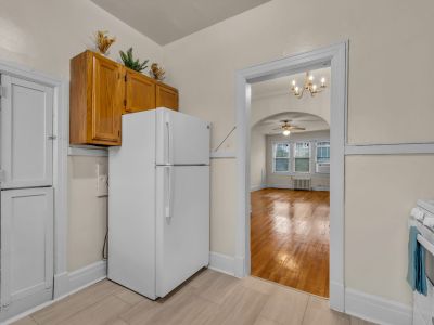 Kitchen space with a white refrigerator leading through an arched doorway into a living room with polished hardwood floors at Midtown Place The Tuscany in Memphis.