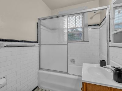 Classic apartment bathroom with white subway wall tile, a frosted glass sliding shower door, and a wood vanity sink at Midtown Place The Tuscany in Memphis.