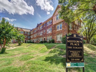Community monument sign on a grassy lawn identifying Midtown Place The Tuscany historic apartment buildings in Memphis.
