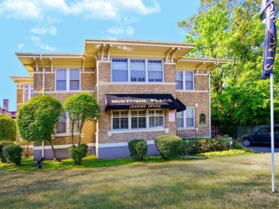 Exterior front view of the historic brick leasing office building with a black awning at Midtown Place apartments in Memphis.