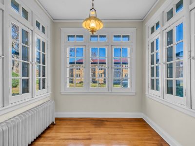 Bright sunroom area featuring original hardwood flooring, a vintage light fixture, and large multi-pane windows at Park Lane Midtown Place apartments in Memphis.