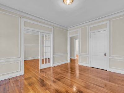 Spacious living room showcasing classic wall molding, polished hardwood floors, and glass French doors in a Park Lane layout at Midtown Place apartments in Memphis.