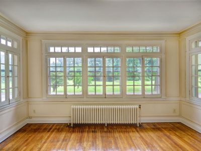 Wide wall of historic multi-pane windows overlooking green courtyard views next to a white radiator at Midtown Place Park lane apartments in Memphis.