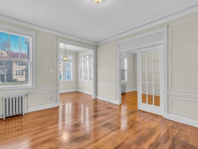 Interior apartment view showcasing connected living spaces with rich hardwood flooring, wall trim, and French doors in Park Lane- Midtown Place in Memphis.