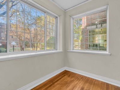 Bright corner sunroom layout featuring historic hardwood floors and distinct multi-pane grid windows inside St. Regis at Midtown Place apartments in Memphis