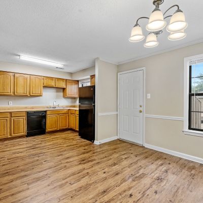 Open dining area and kitchen space featuring oak cabinetry, a black refrigerator, and wood-style flooring at Monticello apartments in Memphis.
