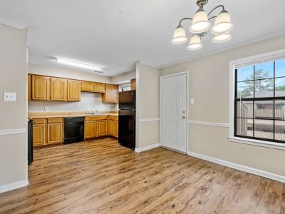 Open dining area and kitchen space featuring oak cabinetry, a black refrigerator, and wood-style flooring at Monticello apartments in Memphis.