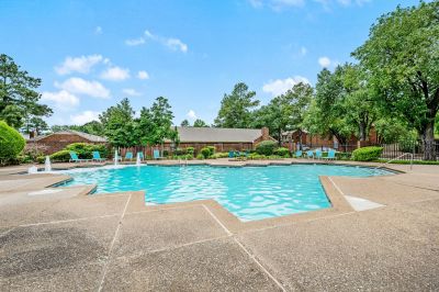 Large outdoor community swimming pool lined with turquoise lounge chairs at Monticello apartments in Memphis.