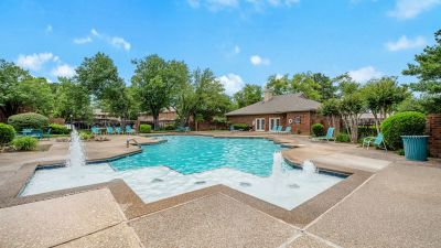Sparkling outdoor swimming pool with water fountains on a sunny day at Monticello apartments in Memphis.