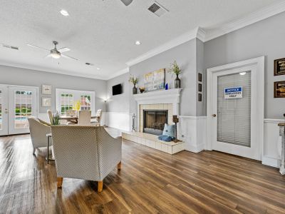 Community clubhouse with wood floors, comfortable armchairs, and a white fireplace mantel at Monticello apartments in Memphis.