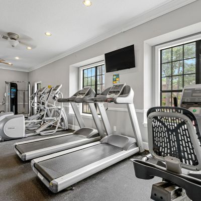 On-site fitness center equipped with treadmills and stationary bikes facing large windows at Monticello apartments in Memphis.