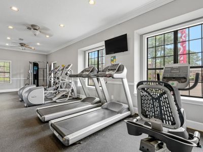 On-site fitness center equipped with treadmills and stationary bikes facing large windows at Monticello apartments in Memphis.