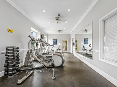 Bright fitness room featuring cardio machines, weight equipment, and a large wall mirror at Monticello apartments in Memphis.