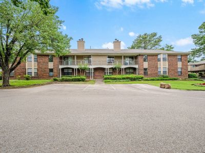 Traditional red brick multi-family residential building featuring a large shared second-story balcony at Monticello apartments in Memphis.