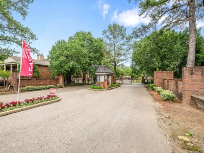 Gated community entrance with a central guard house booth and brick accent walls at Monticello apartments in Memphis.