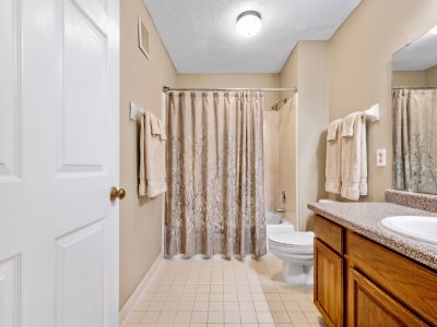 Bathroom featuring a wood vanity with a neutral countertop and a patterned shower curtain at Monticello apartments in Memphis.