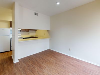 Open dining space featuring wood-look vinyl plank flooring and a breakfast bar cutout looking into the kitchen area at Pinewood Manor apartments and townhomes in Memphis.