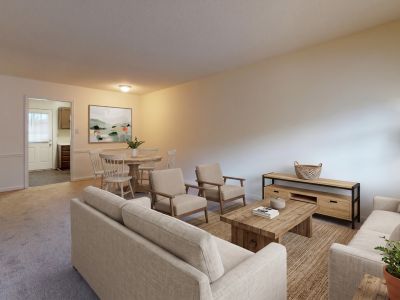 living room layout with neutral couches, light wood tables, a woven rug, and a separate dining area at Pinewood Manor apartments and townhomes in Memphis.